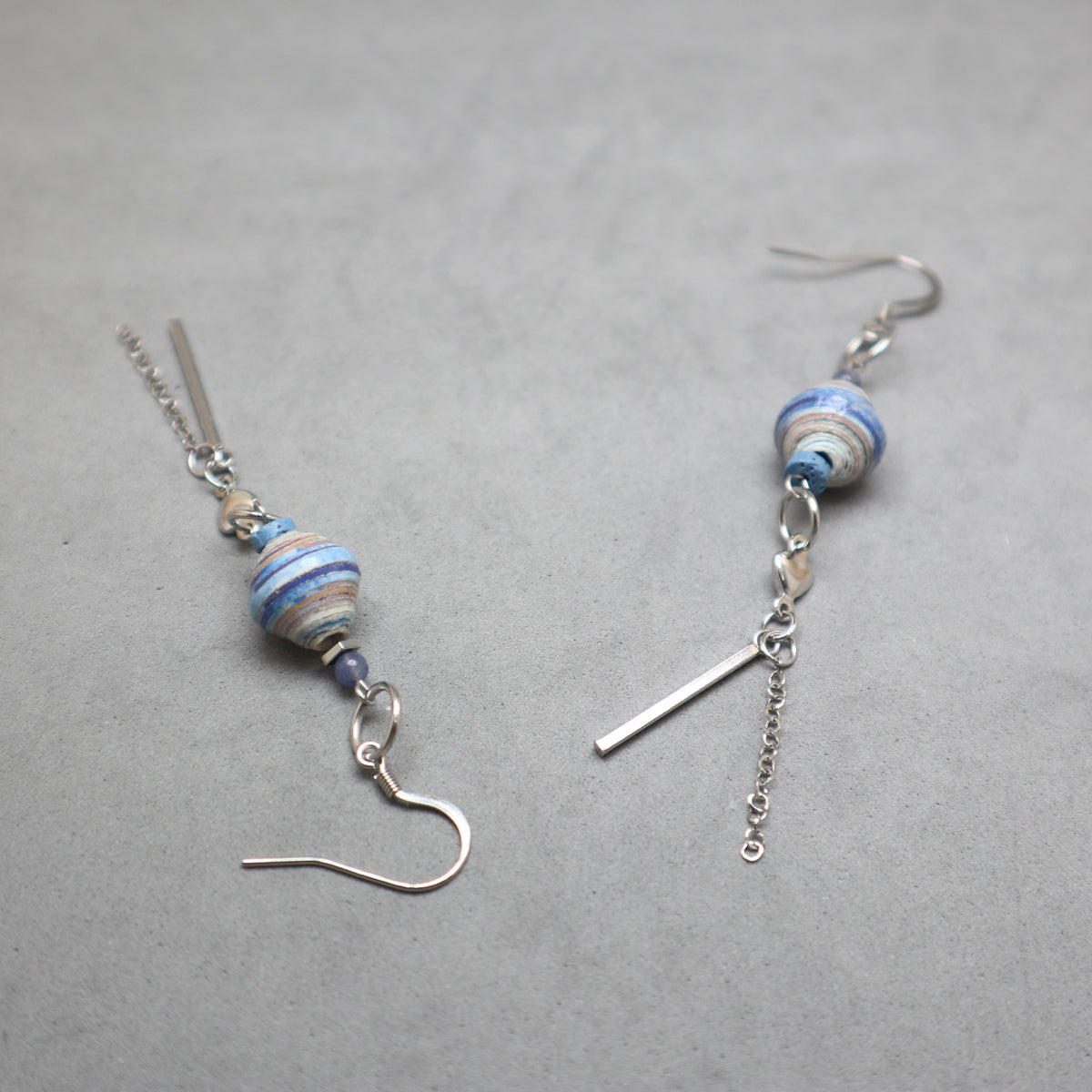 Pair of gold triangle and beaded earrings on a gray background
