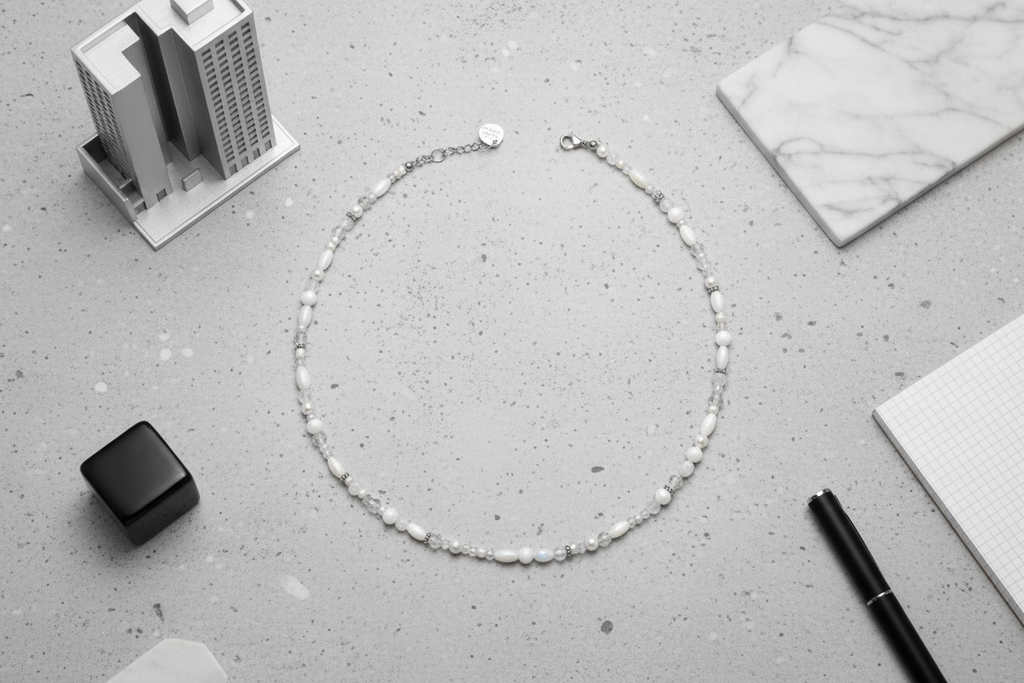Silver necklace on a gray surface with office supplies in the background, white and silver
