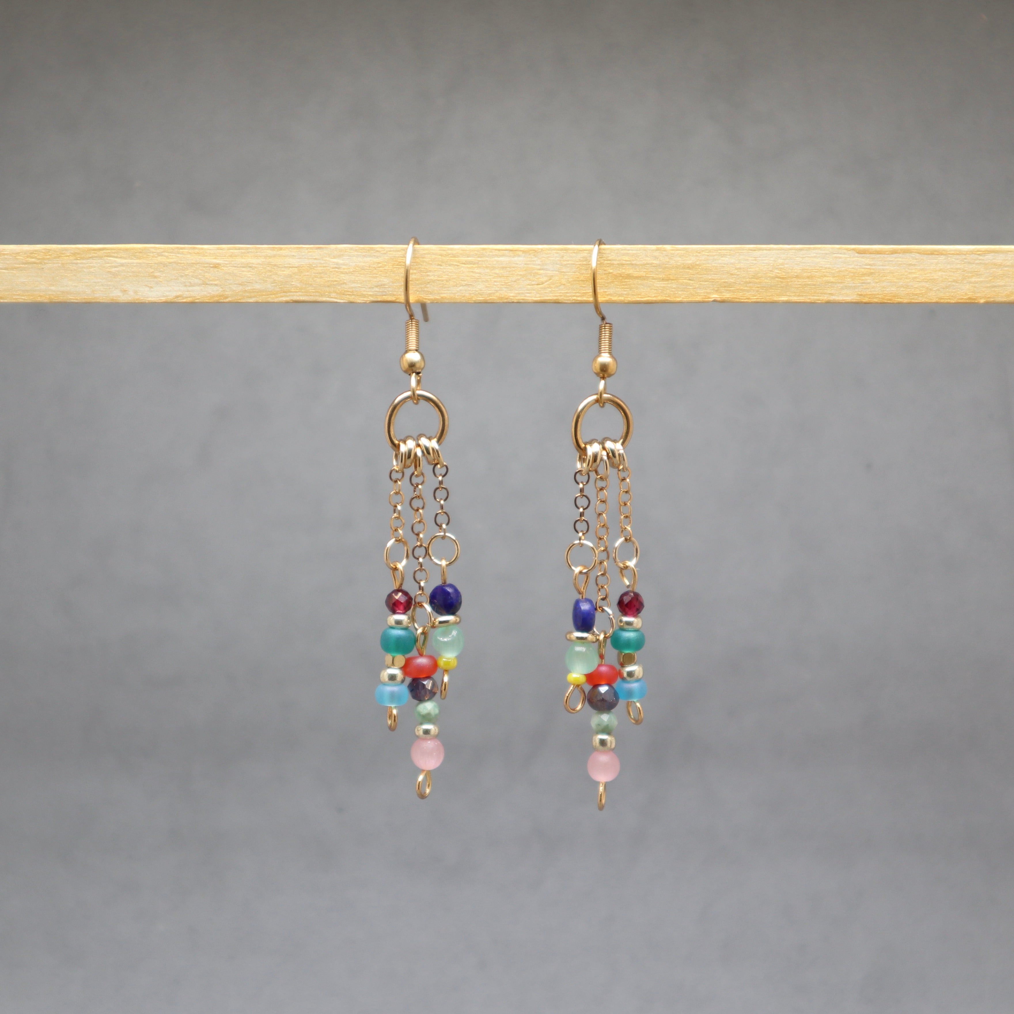 Multicolored beaded earrings on a gray background, stainless steel gold