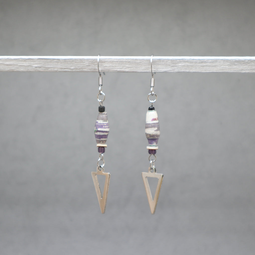 Pair of earrings with geometric designs on a gray background. Paper beads violet with silver arrows