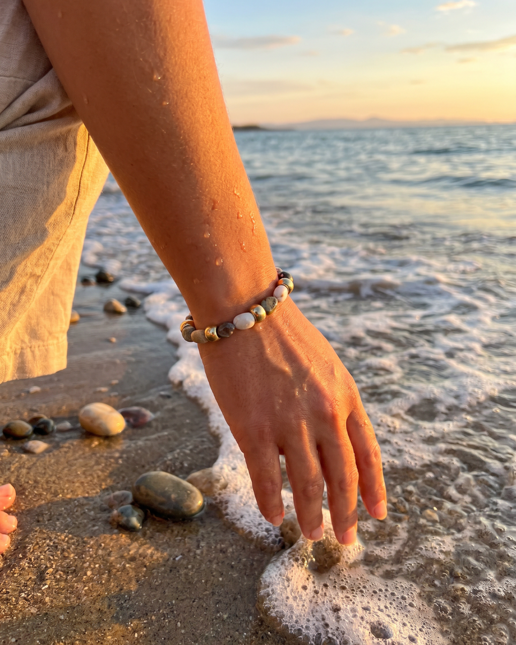 a hand wearing the sable bracelet by the ocean