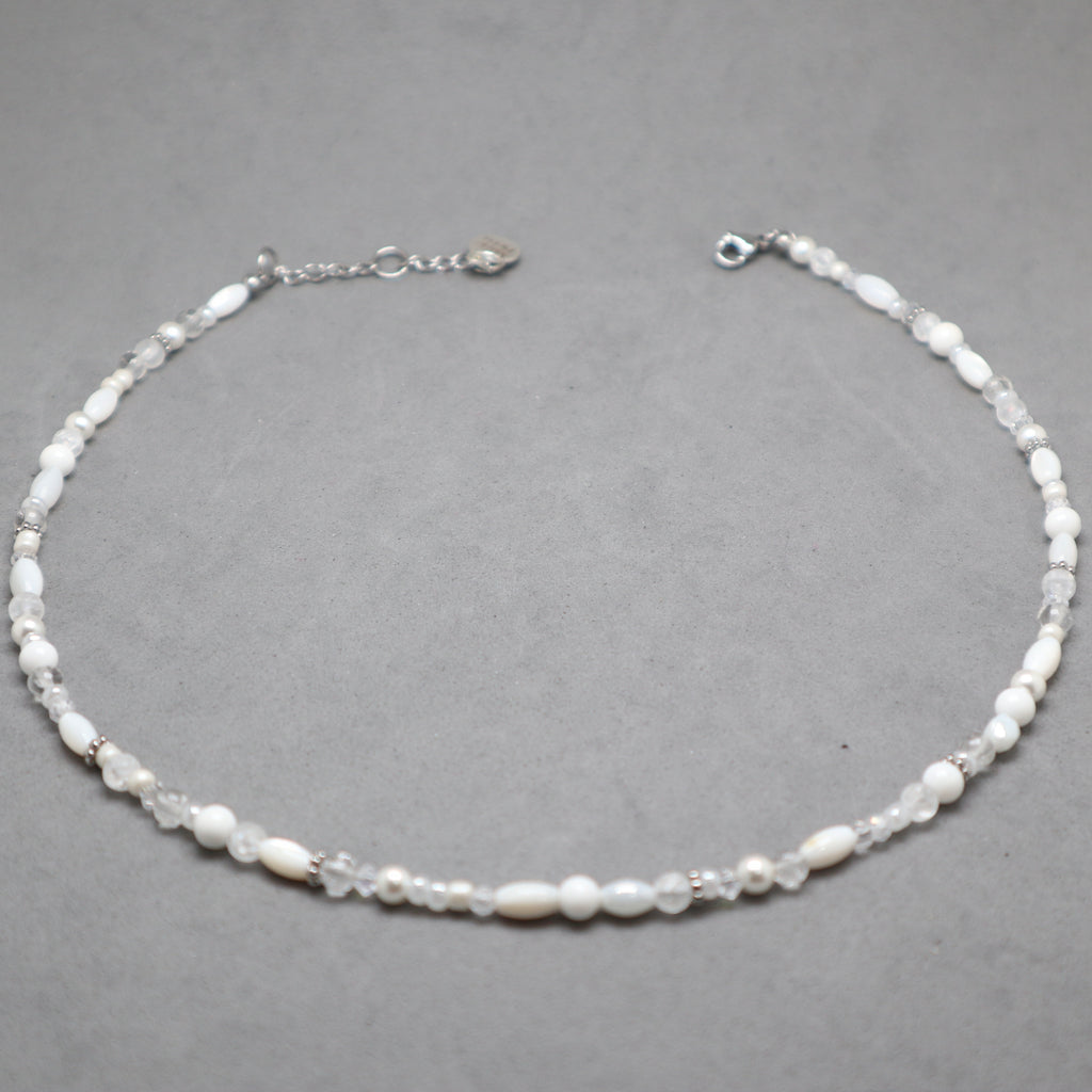 Necklace with white beads on a gray background, white and silver necklace for women