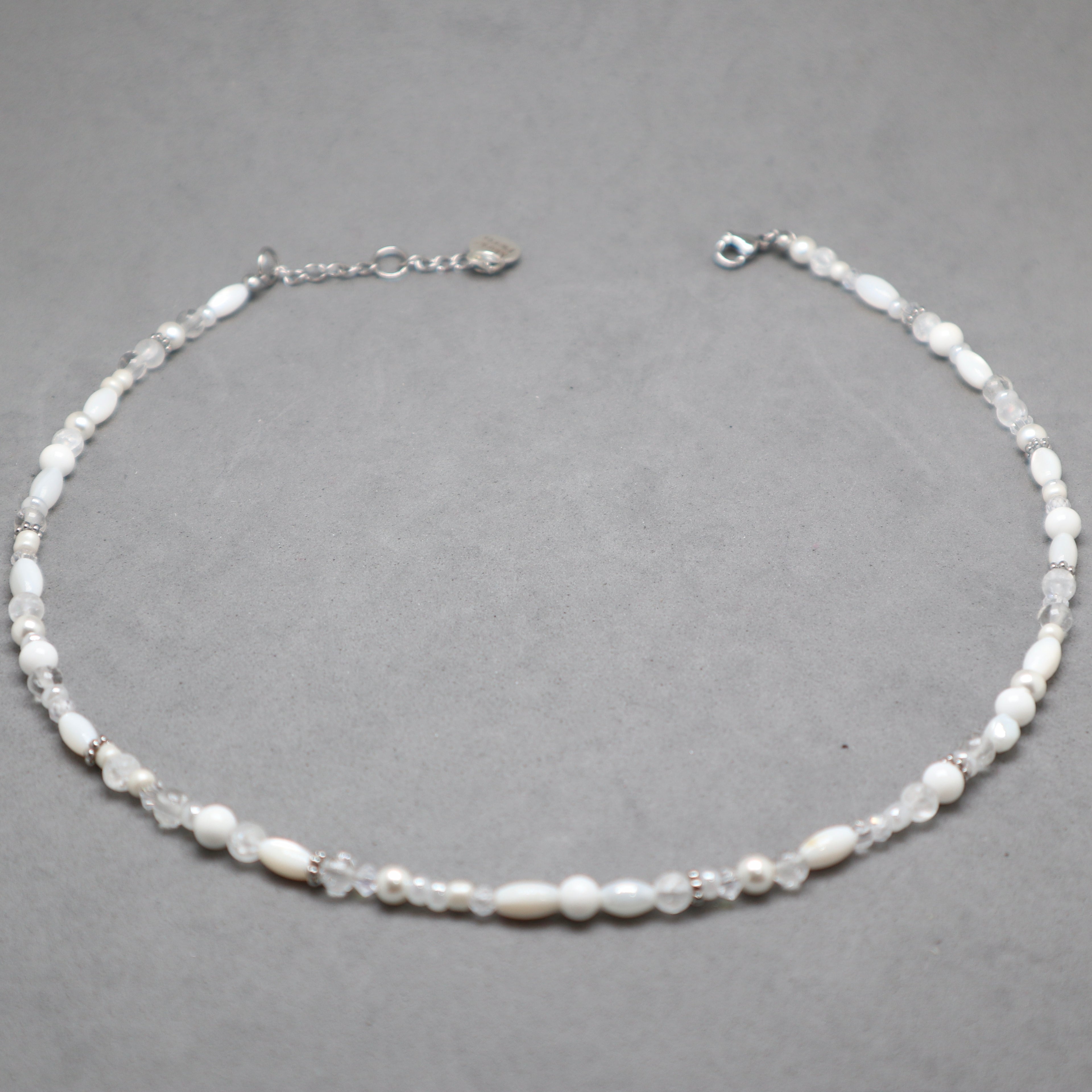 Necklace with white beads on a gray background, white and silver necklace for women