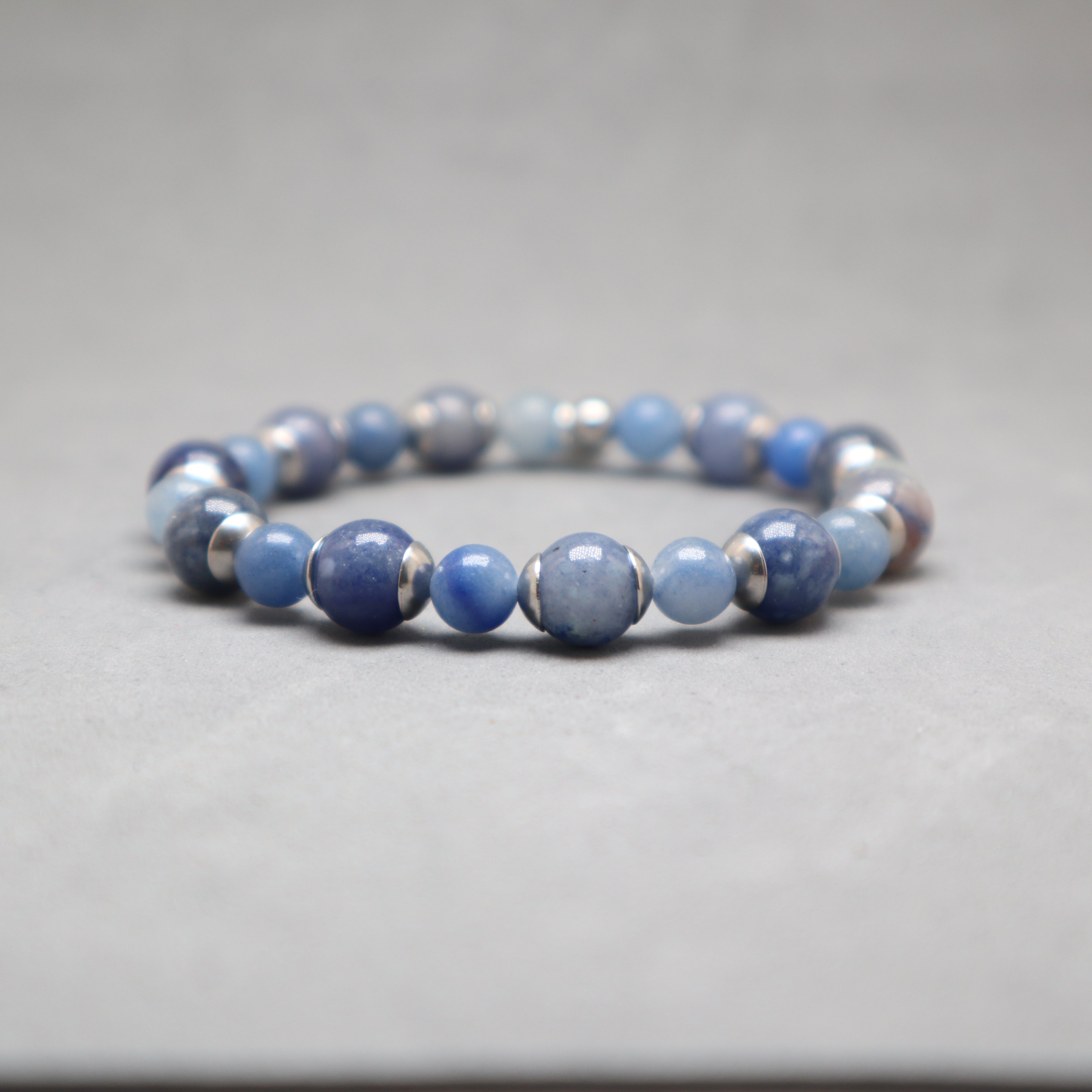 Blue beaded bracelet with silver accents on a gray background, aventurine, stainless steel