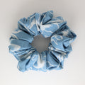 Blue and white patterned scrunchie on a light gray background