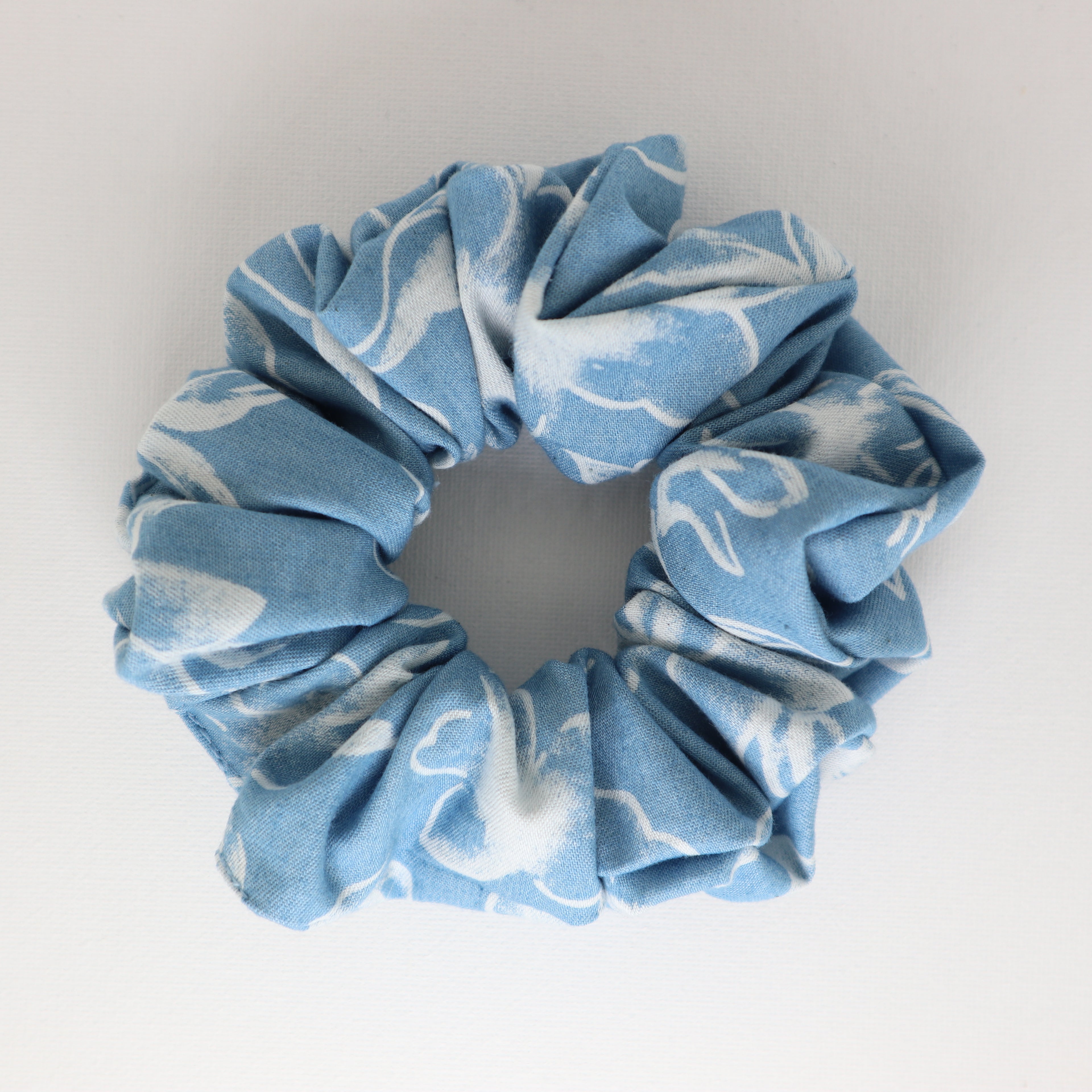 Blue and white patterned scrunchie on a light gray background