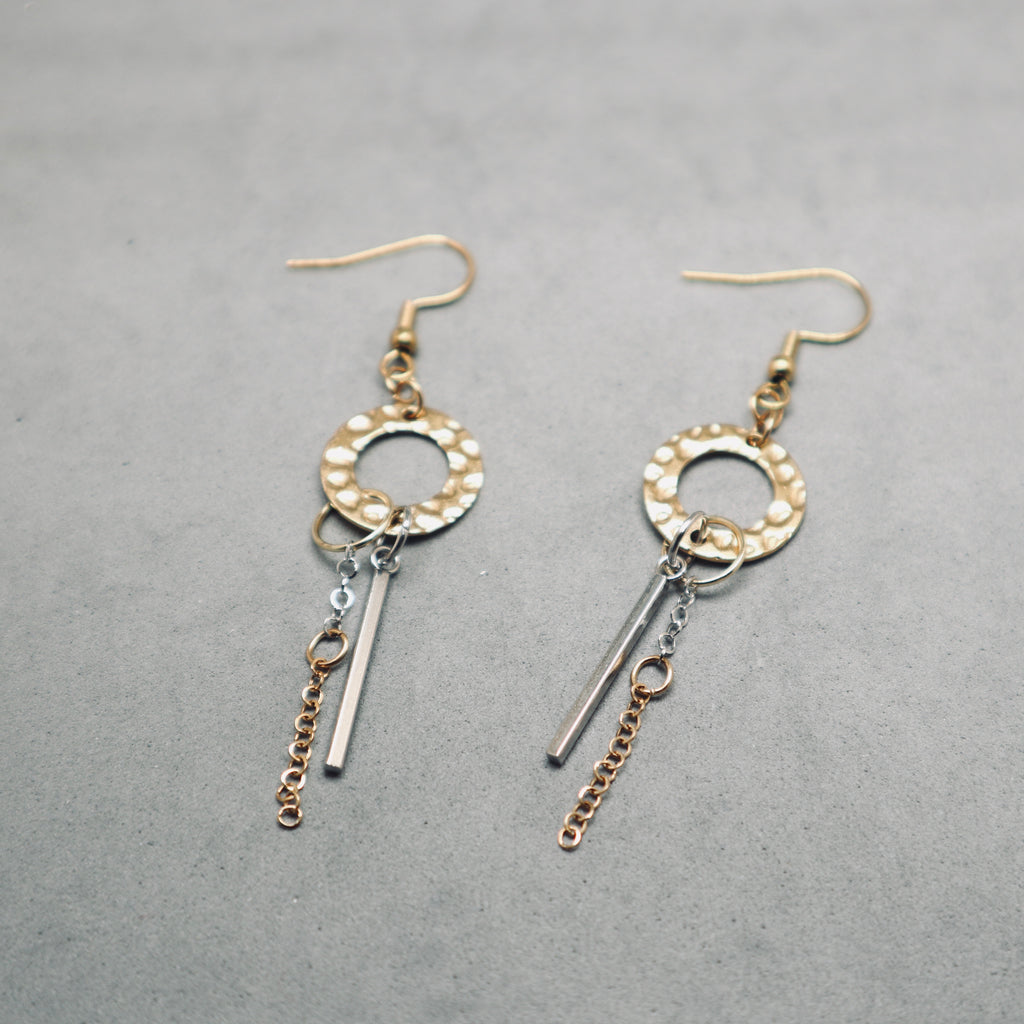 Pair of gold and silver earrings on a gray background