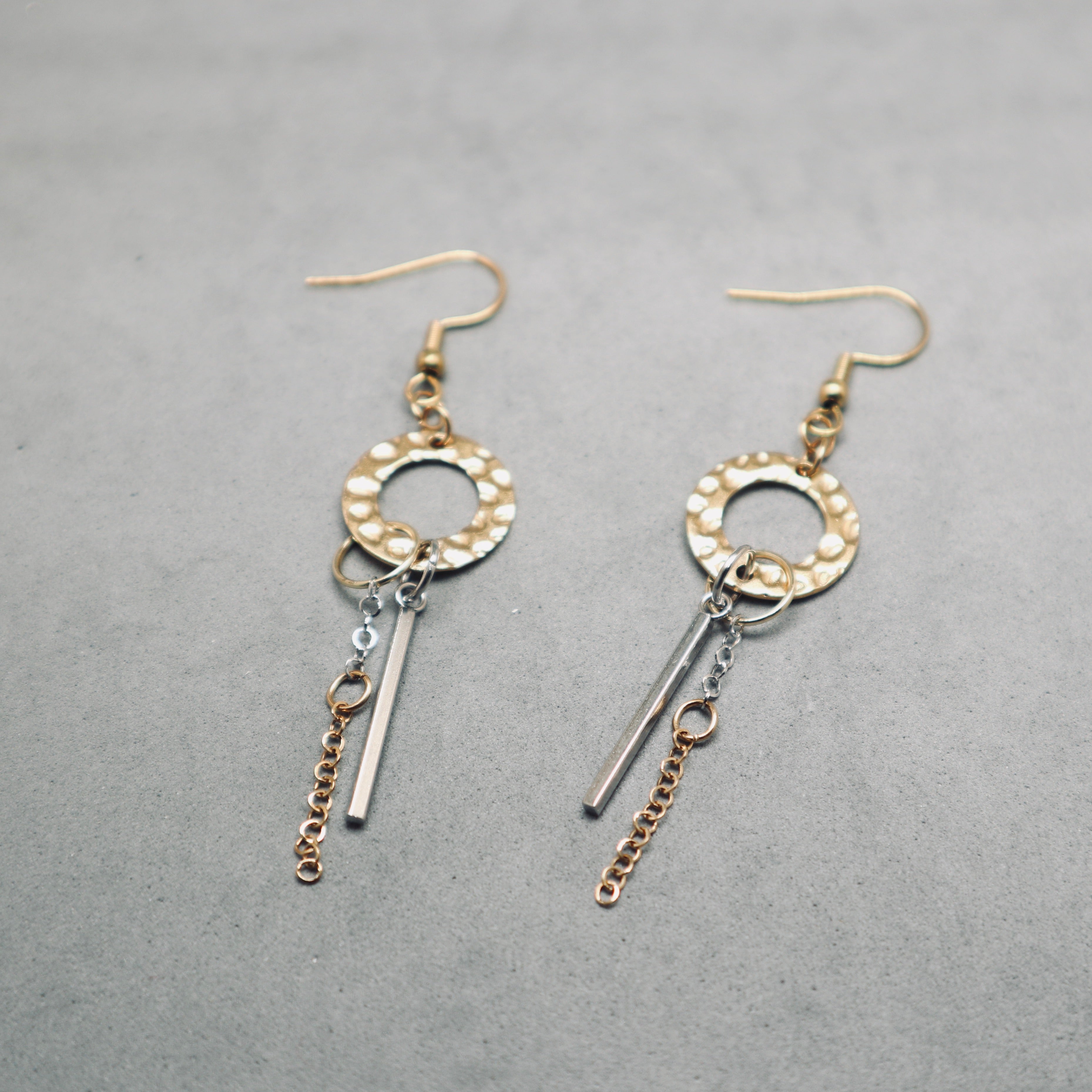 Pair of gold and silver earrings on a gray background