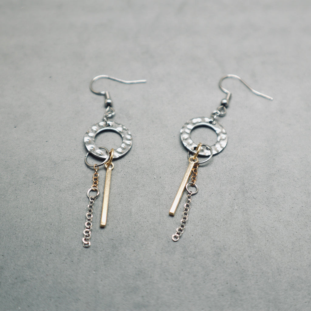 Pair of silver earrings with gold accents on a gray background