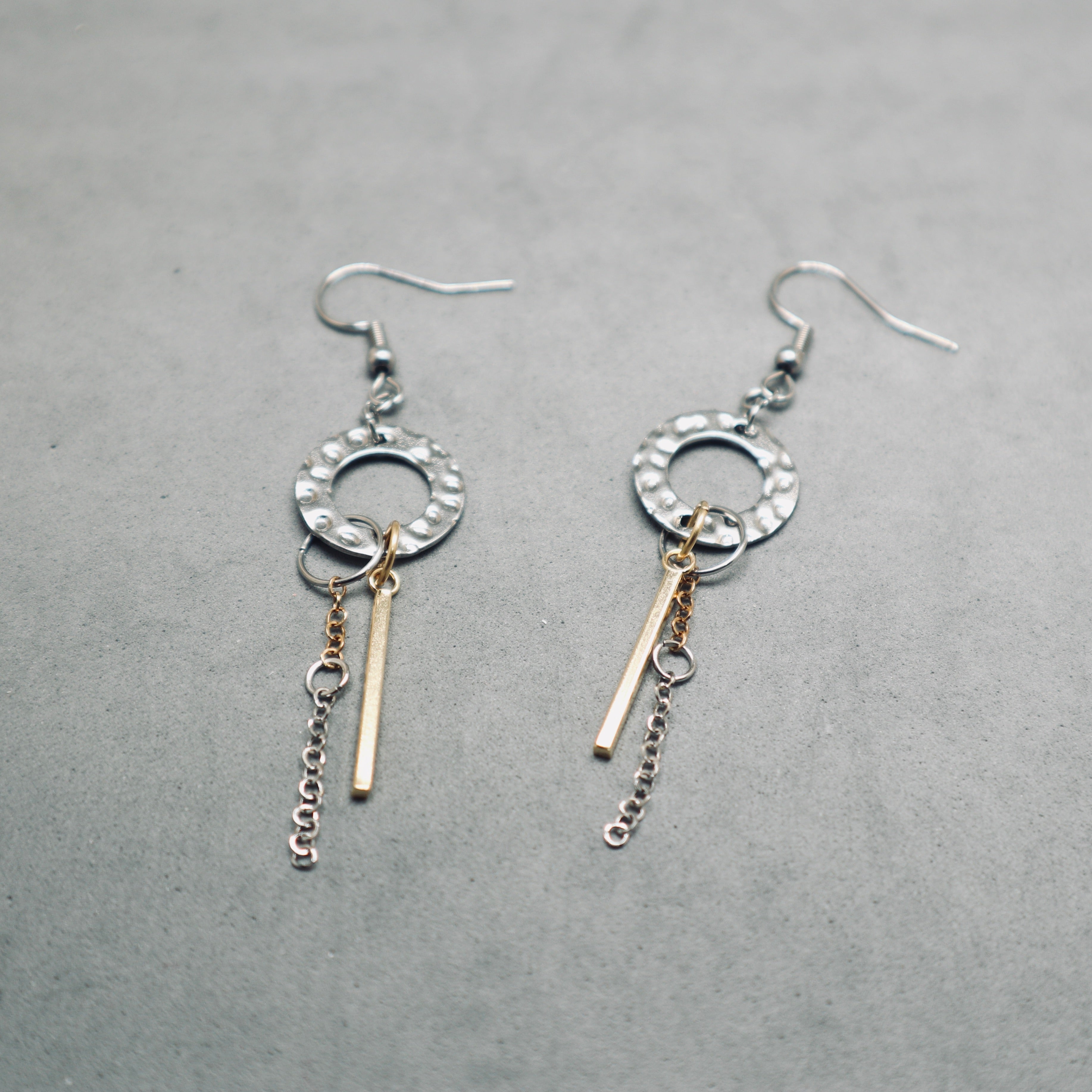 Pair of silver earrings with gold accents on a gray background