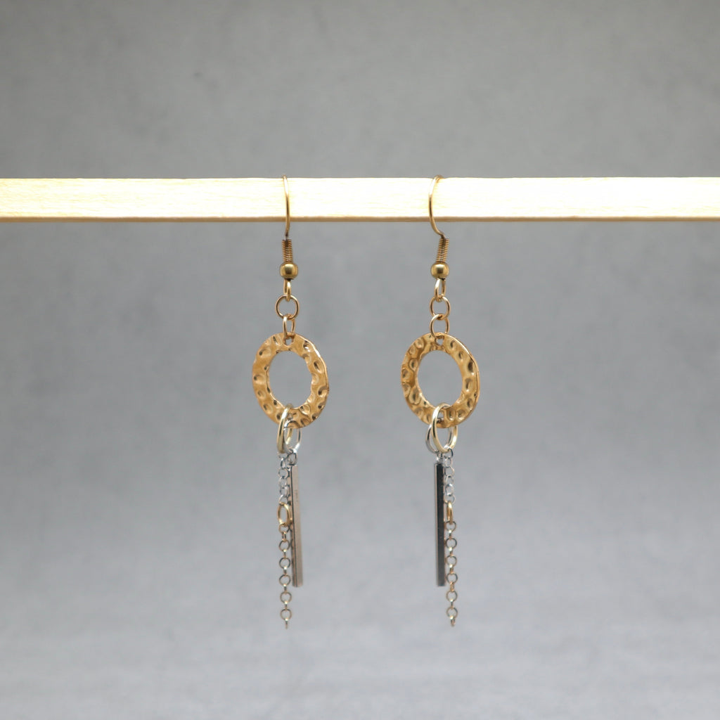 Gold and silver earrings hanging on a gray background
