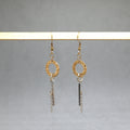 Gold and silver earrings hanging on a gray background