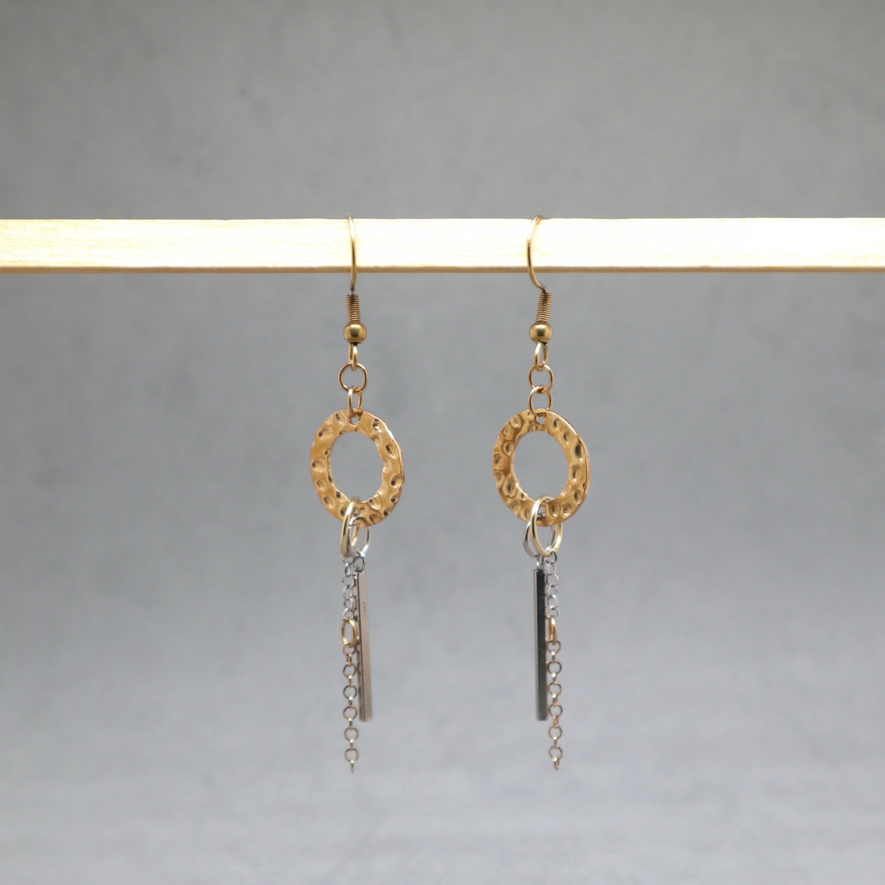 Gold and silver earrings hanging on a gray background