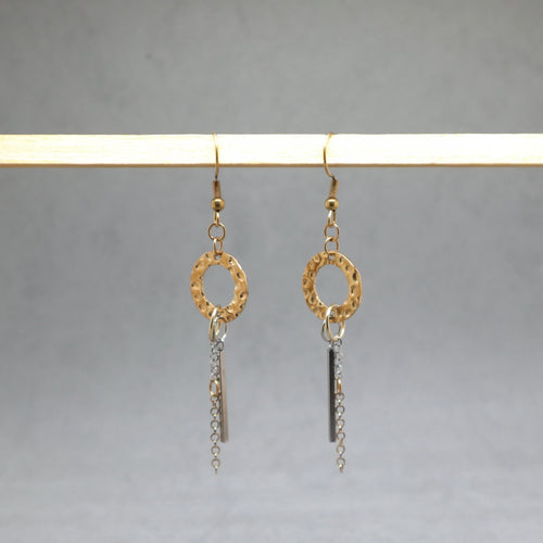 Gold and silver earrings hanging on a gray background