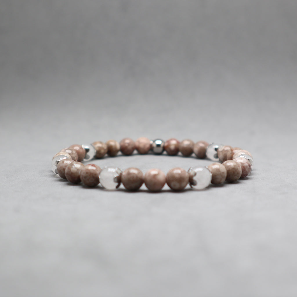 A beaded stretch bracelet featuring round brown and beige stone beads with a few polished silver metallic accent beads, displayed on a neutral gray background.