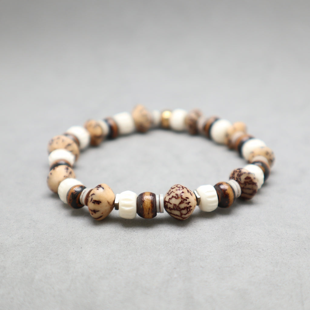 A beaded stretch bracelet made of alternating cream, brown, and dark brown marbled beads, displayed on a neutral gray background.