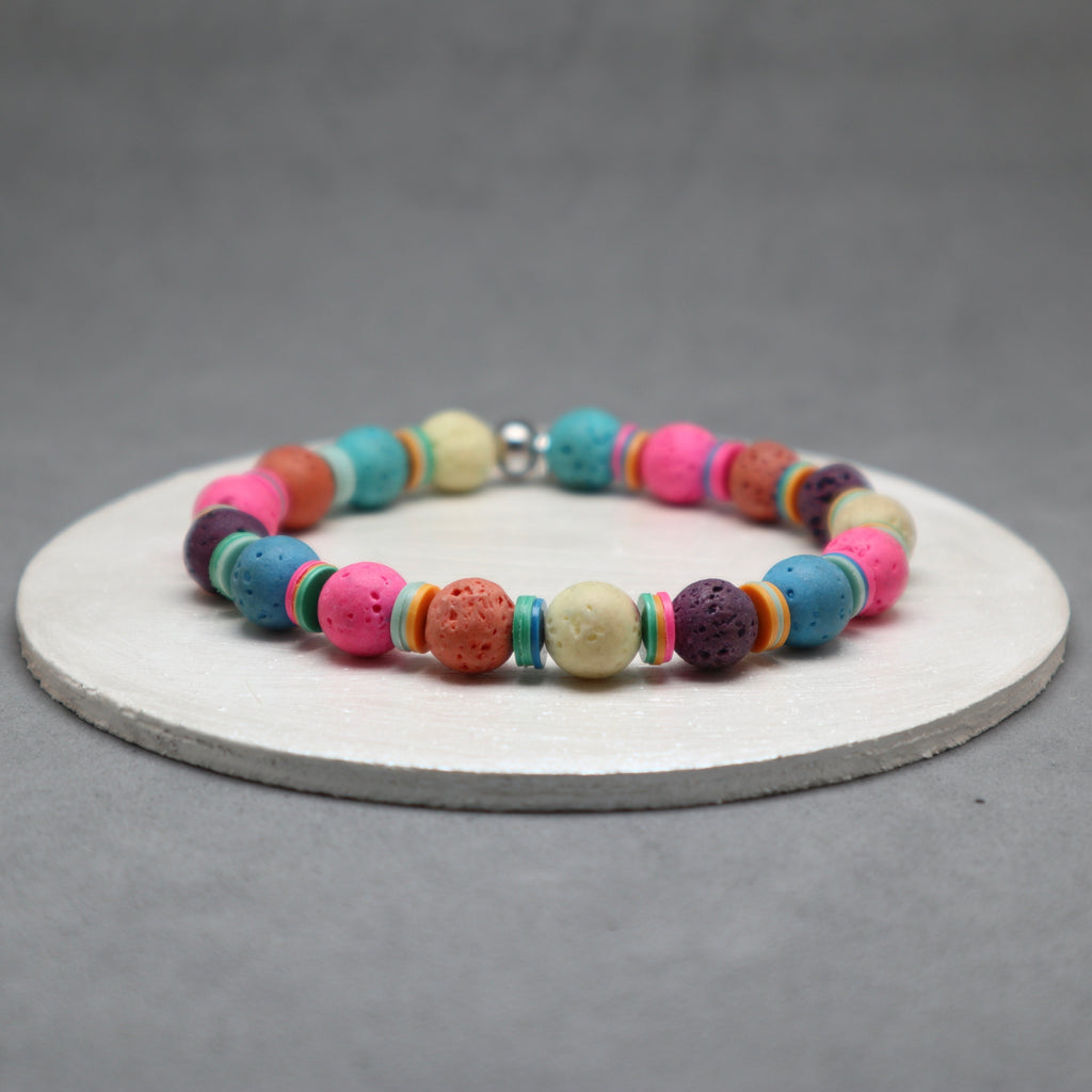Colorful beaded bracelet on a white circular stand with a gray background, colorful lava, disk heishi