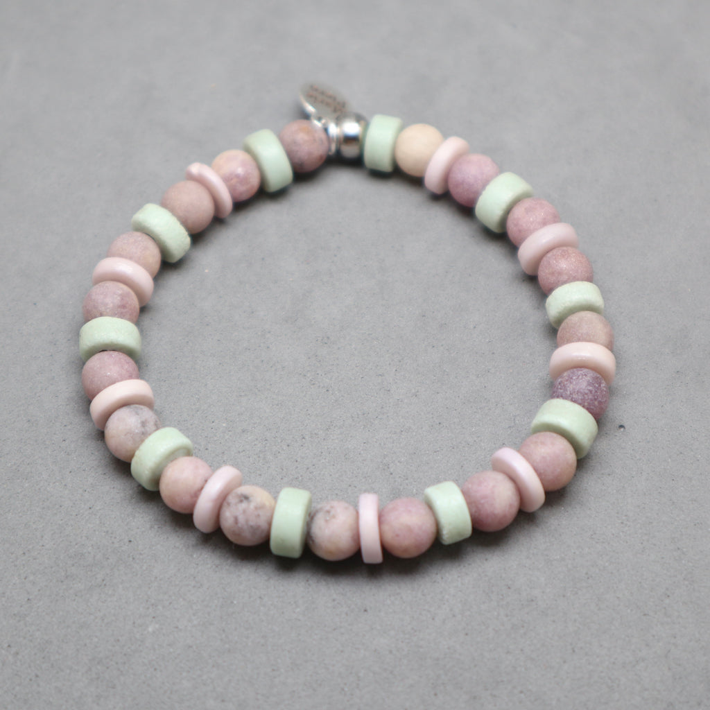 Beaded bracelet with pink and green beads on a gray background