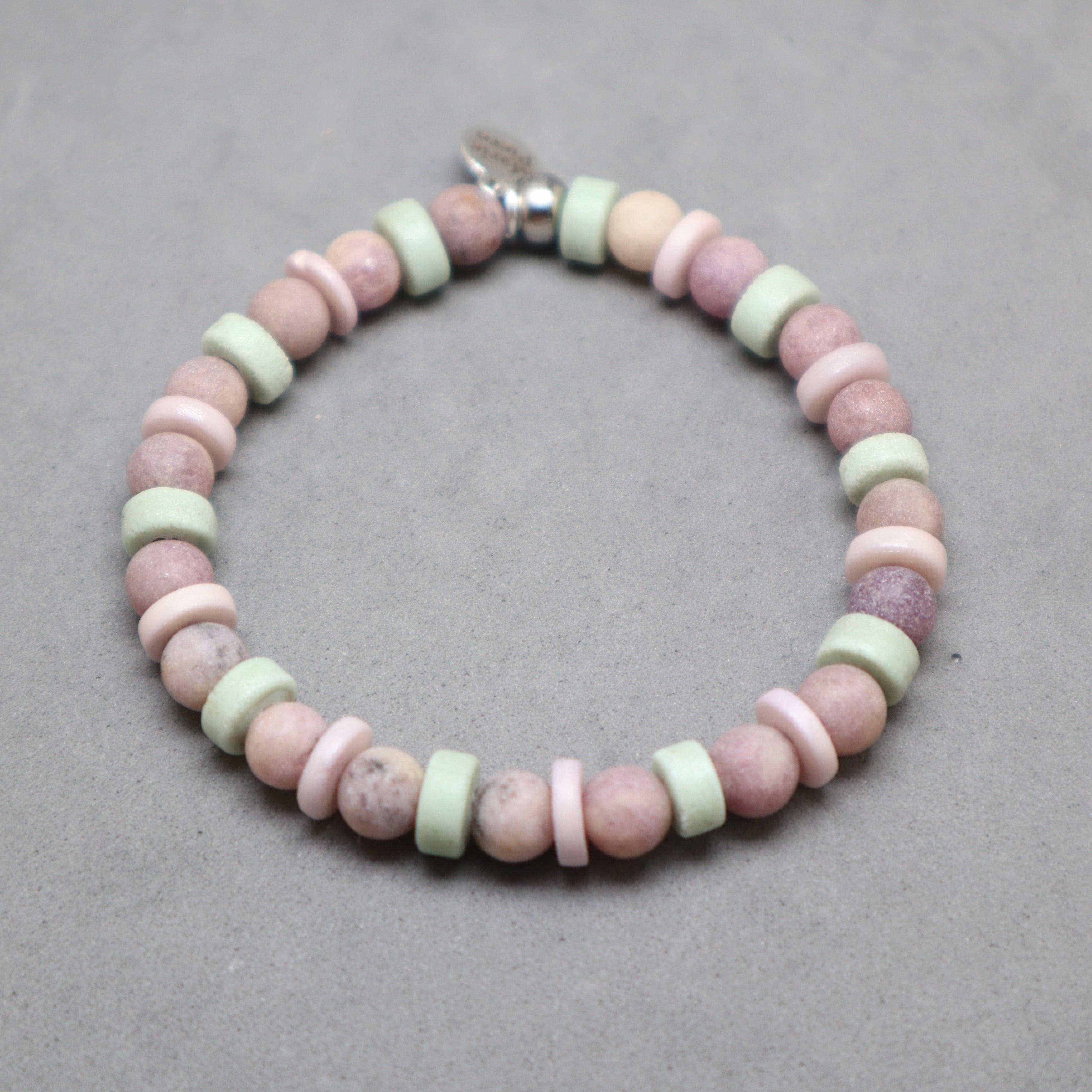 Beaded bracelet with pink and green beads on a gray background