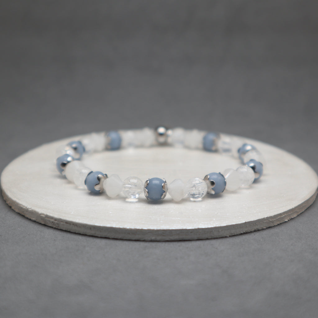 Beaded bracelet with blue and clear beads on a gray background, angelite, stainless steel, quartz bicone and cracked