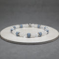 Beaded bracelet with blue and clear beads on a gray background, angelite, stainless steel, quartz bicone and cracked
