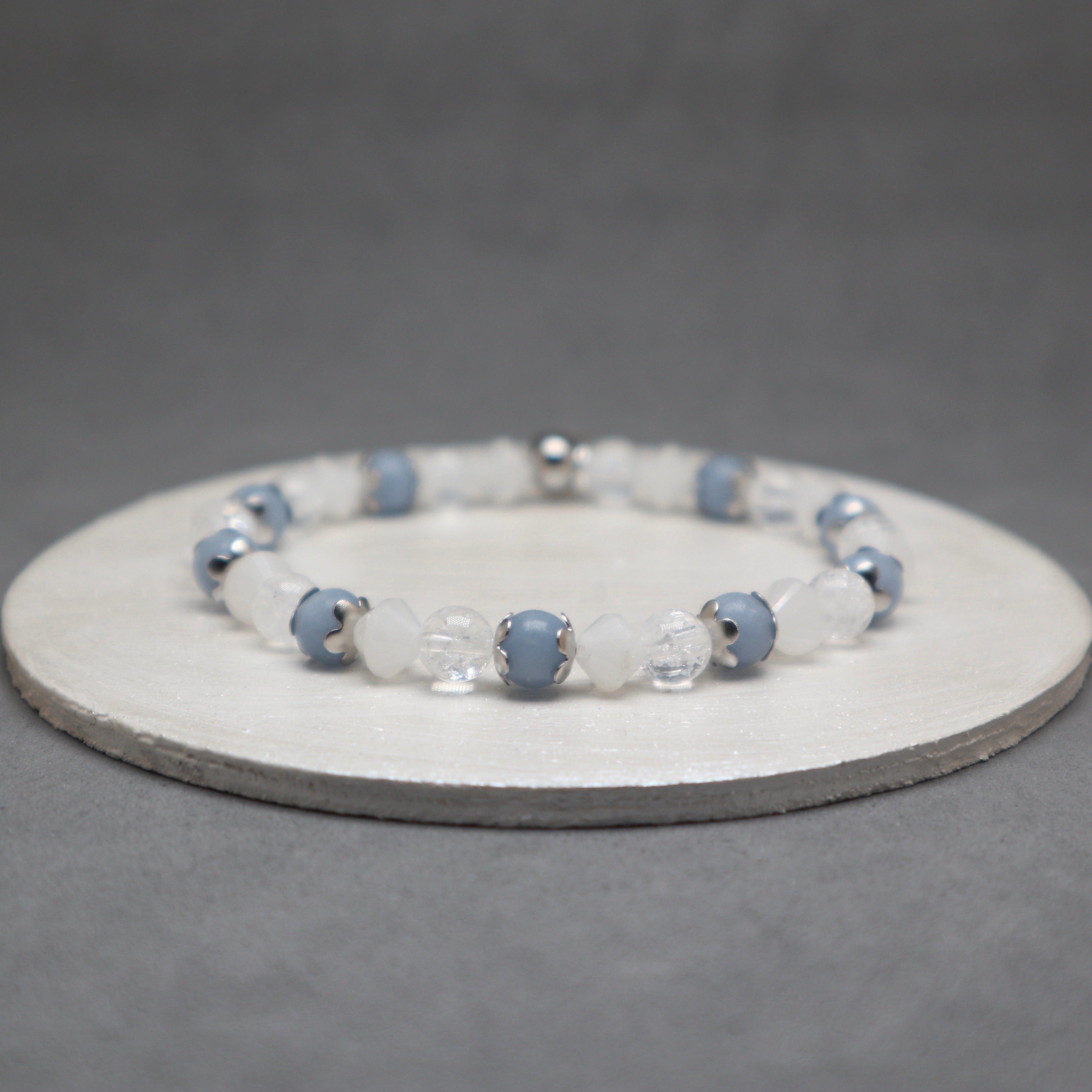 Beaded bracelet with blue and clear beads on a gray background, angelite, stainless steel, quartz bicone and cracked