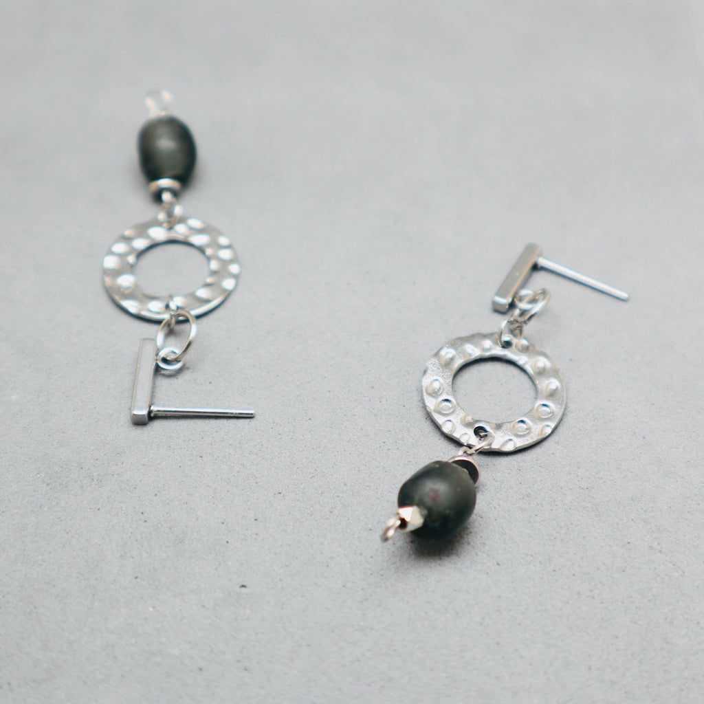 Silver earrings with black beads on a gray background