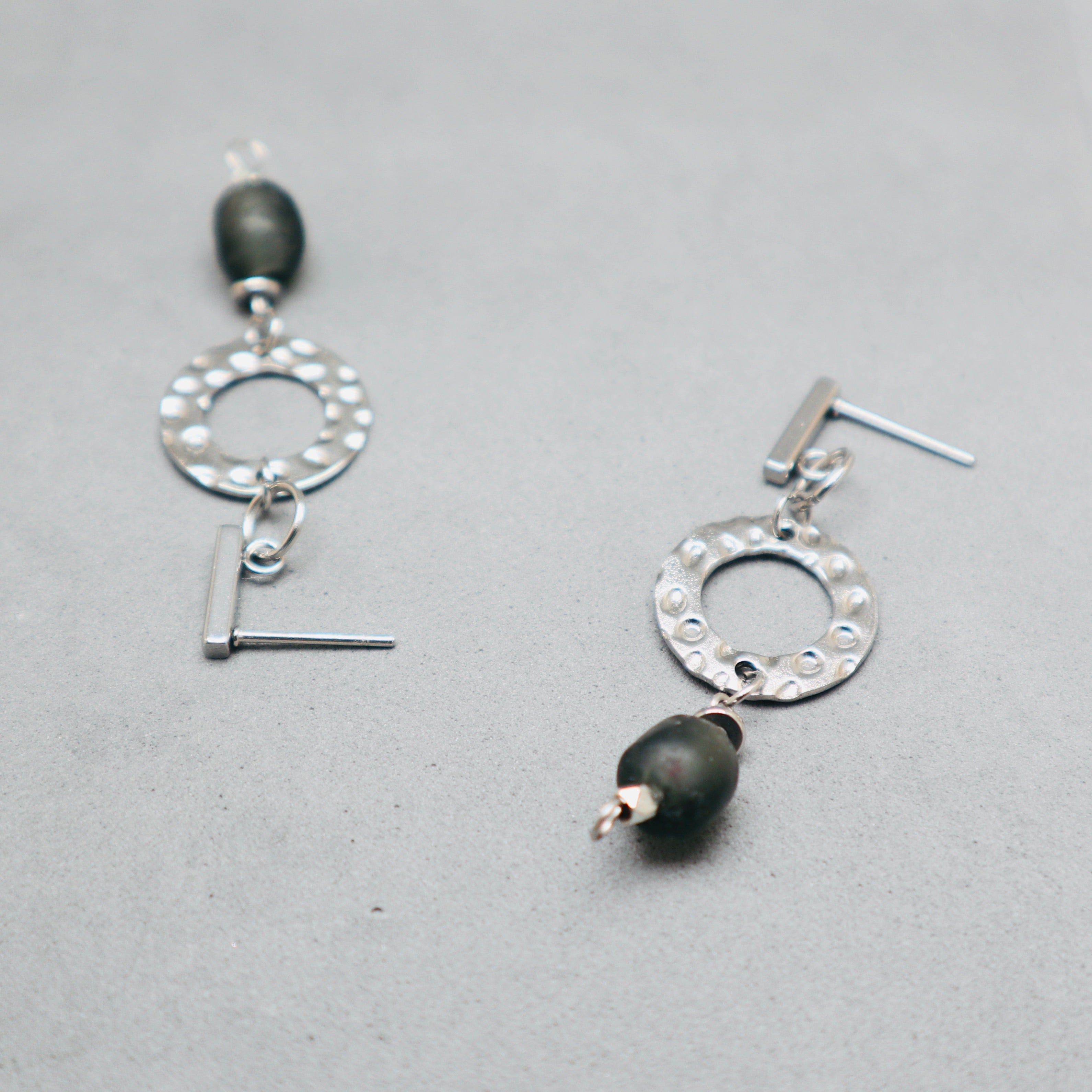 Silver earrings with black beads on a gray background