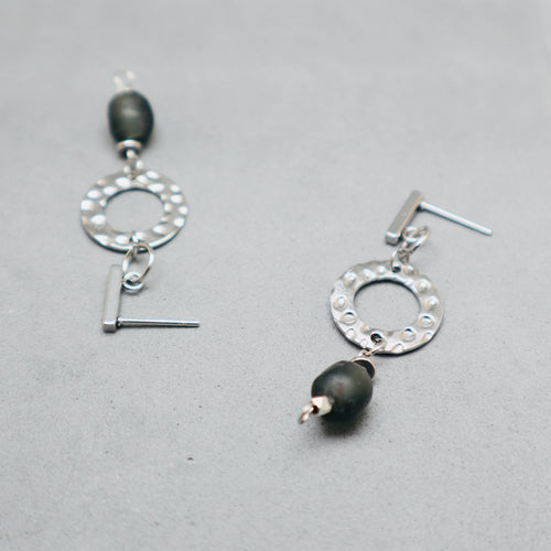 Silver earrings with black beads on a gray background