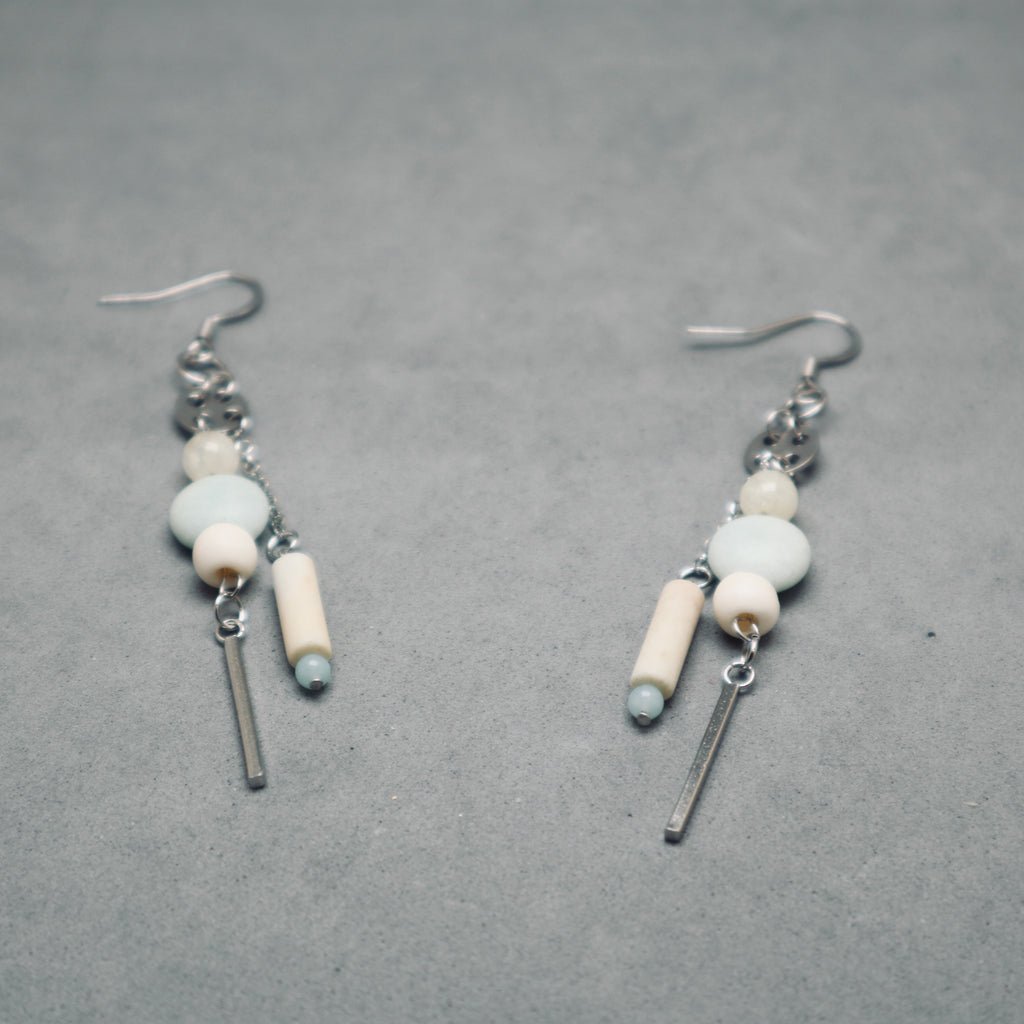 Pair of earrings with beads and bars on a gray background