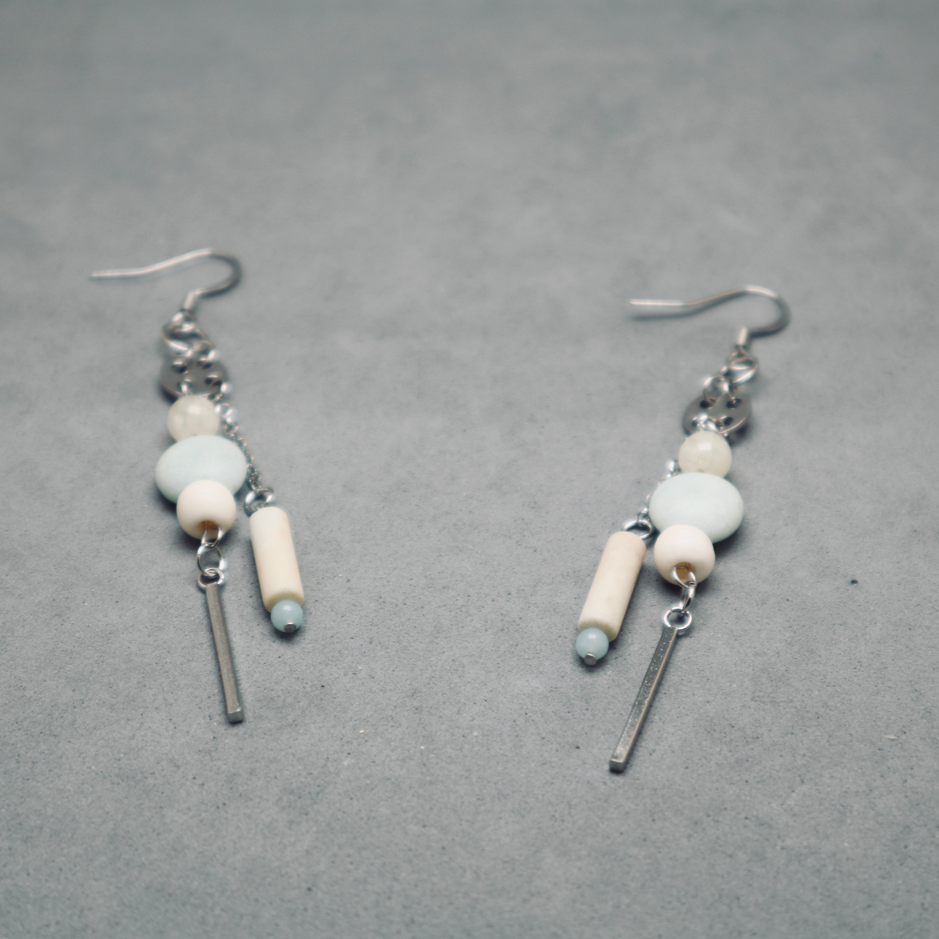Pair of earrings with beads and bars on a gray background