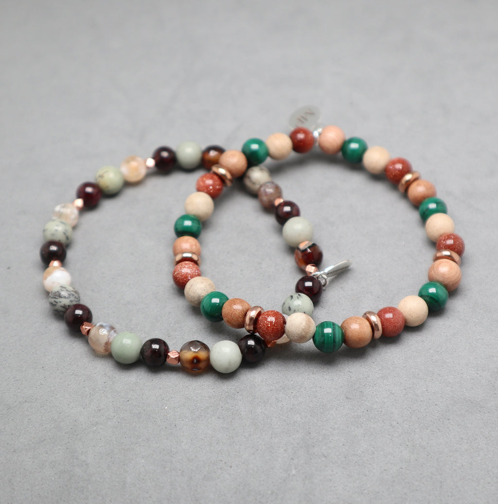 Multicolored beaded bracelet on a gray background, malachite, gold stone, rosewood, garnet, jasper pine tree