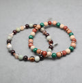 Multicolored beaded bracelet on a gray background, malachite, gold stone, rosewood, garnet, jasper pine tree
