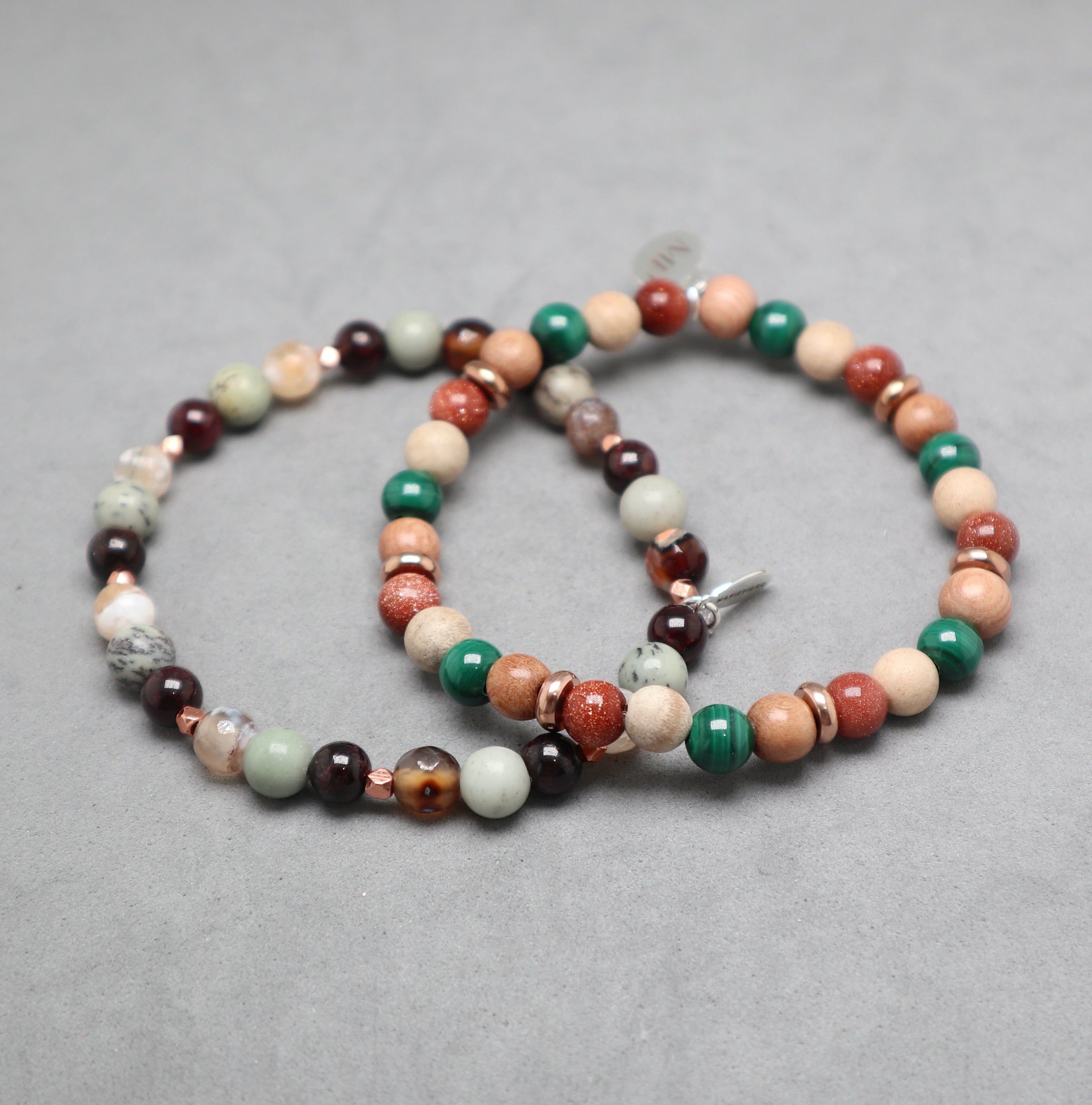 Multicolored beaded bracelet on a gray background, malachite, gold stone, rosewood, garnet, jasper pine tree