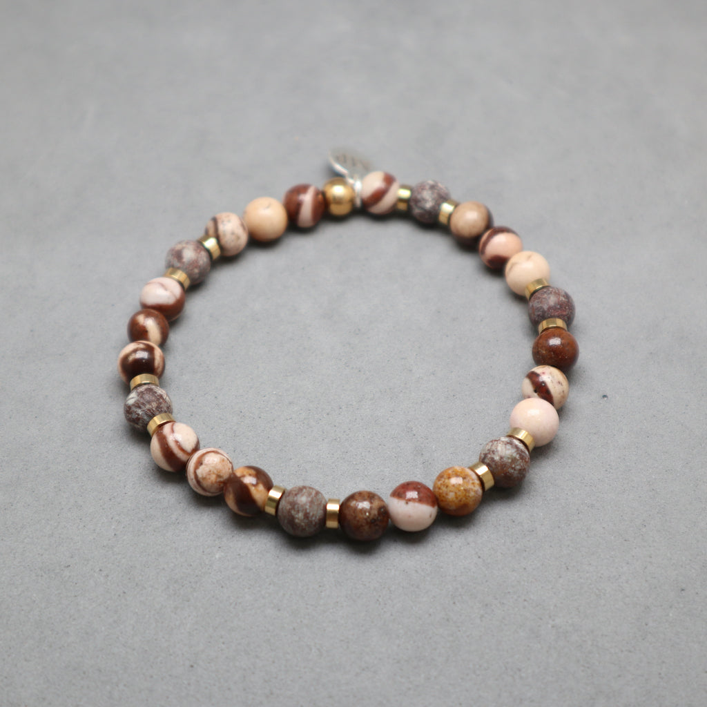 Beaded bracelet with brown, beige, and gold beads on a gray background