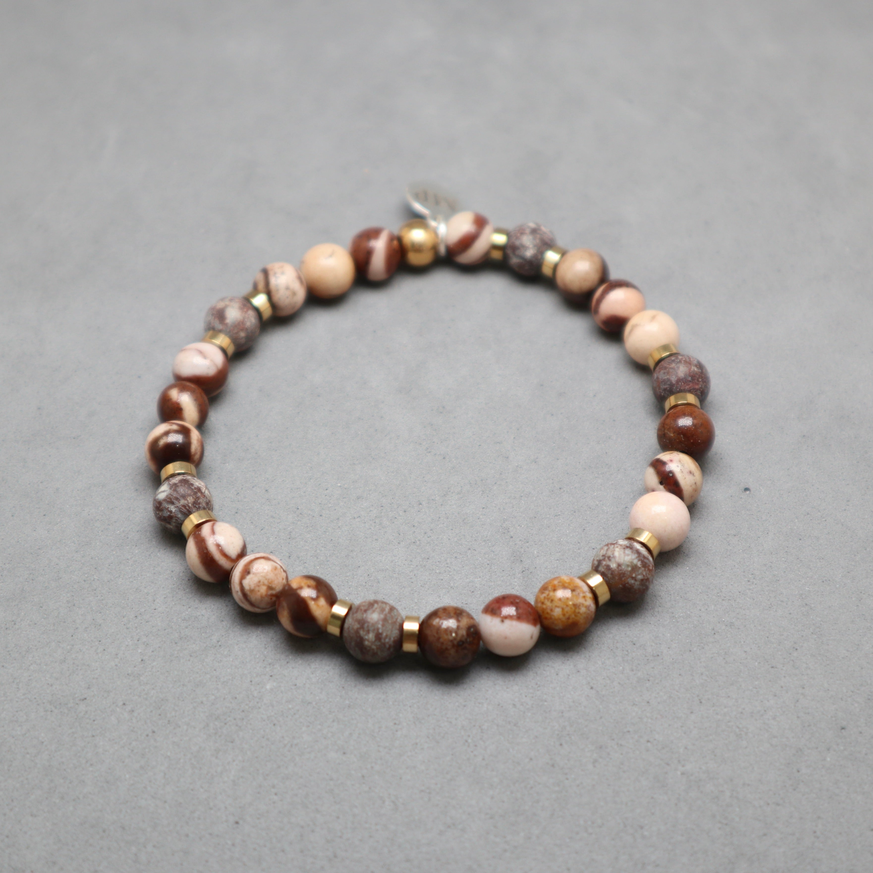 Beaded bracelet with brown, beige, and gold beads on a gray background