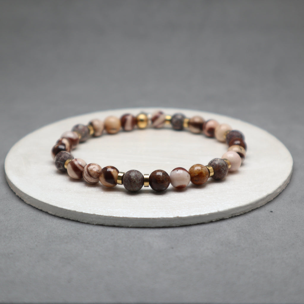 Beaded bracelet on a round stone surface with a gray background,zebra jasper, stainless steel