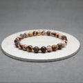 Beaded bracelet on a round stone surface with a gray background,zebra jasper, stainless steel
