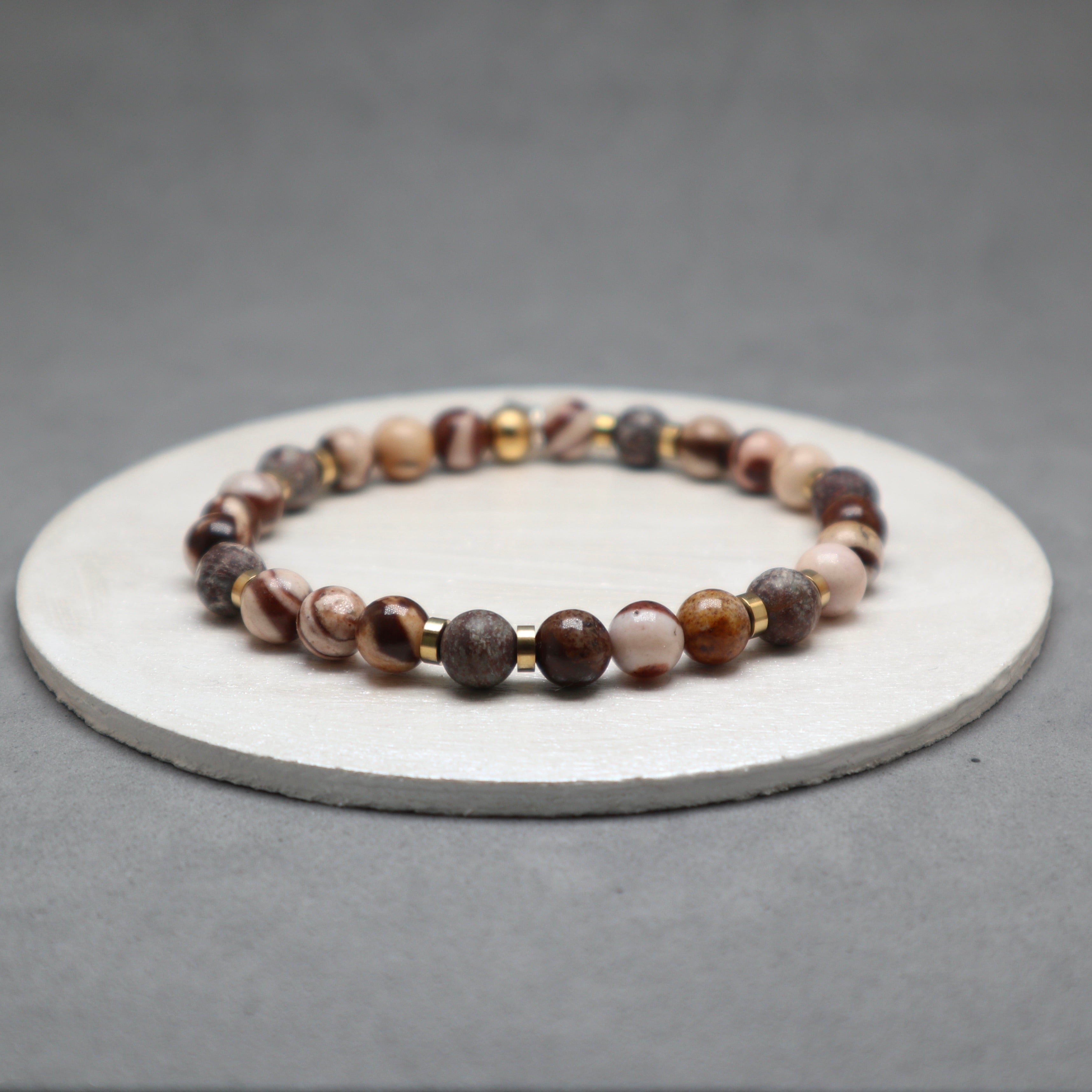 Beaded bracelet on a round stone surface with a gray background,zebra jasper, stainless steel
