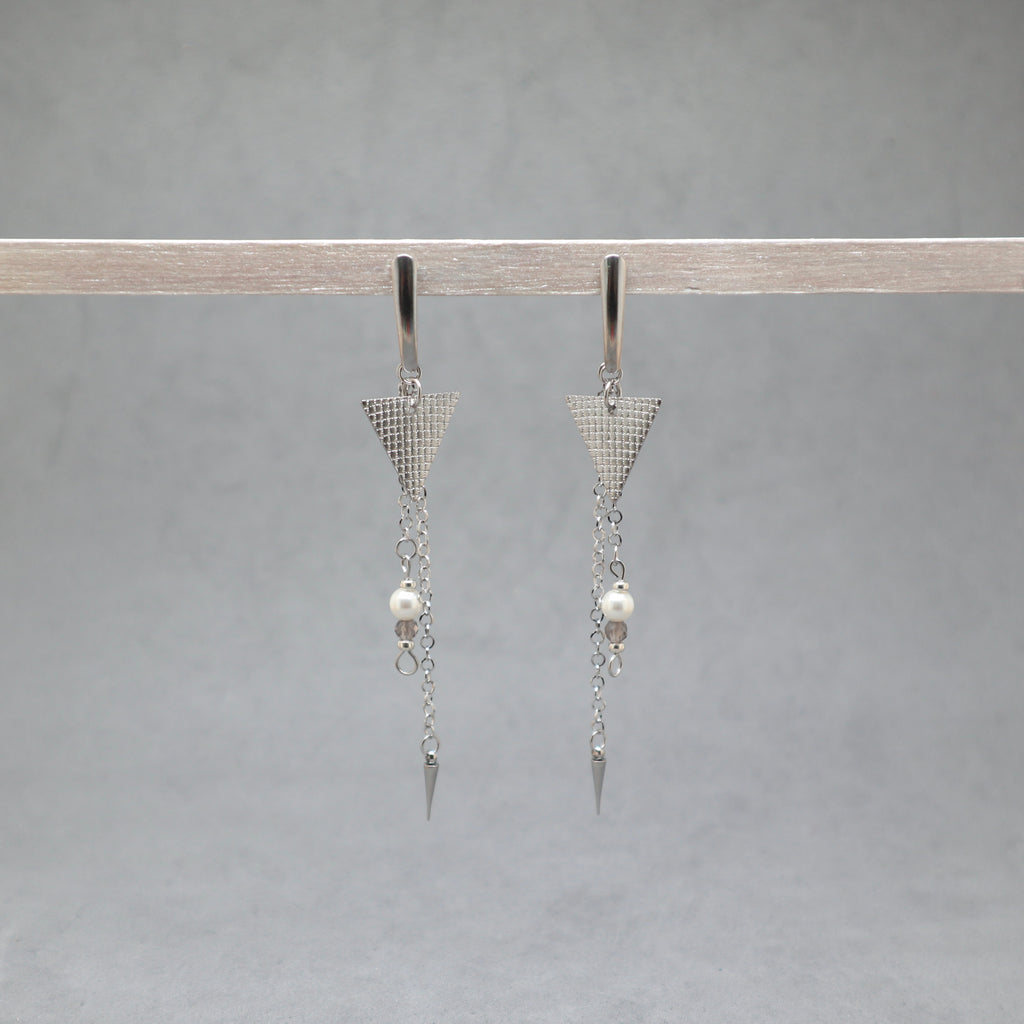 Pair of silver triangle earrings with pearl drops on a gray background