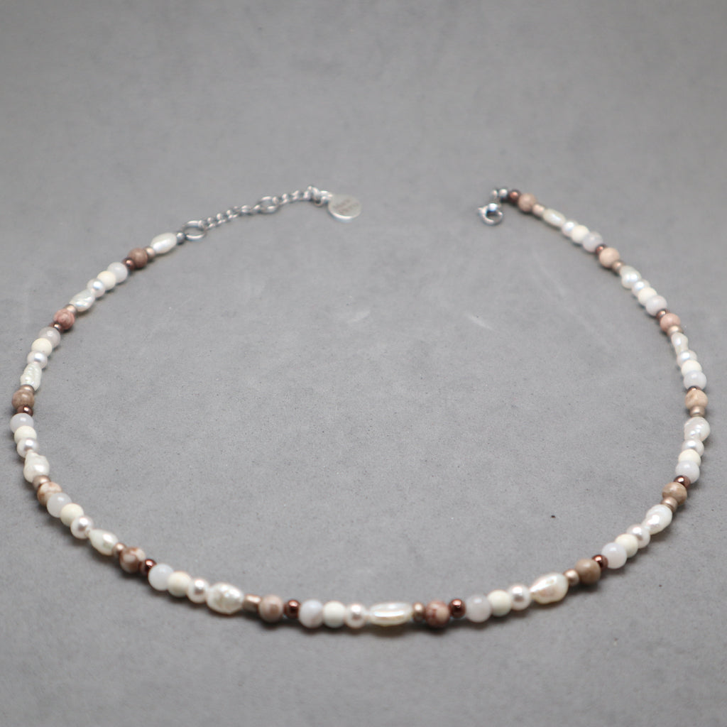 Necklace with pearls and brown beads on a gray background