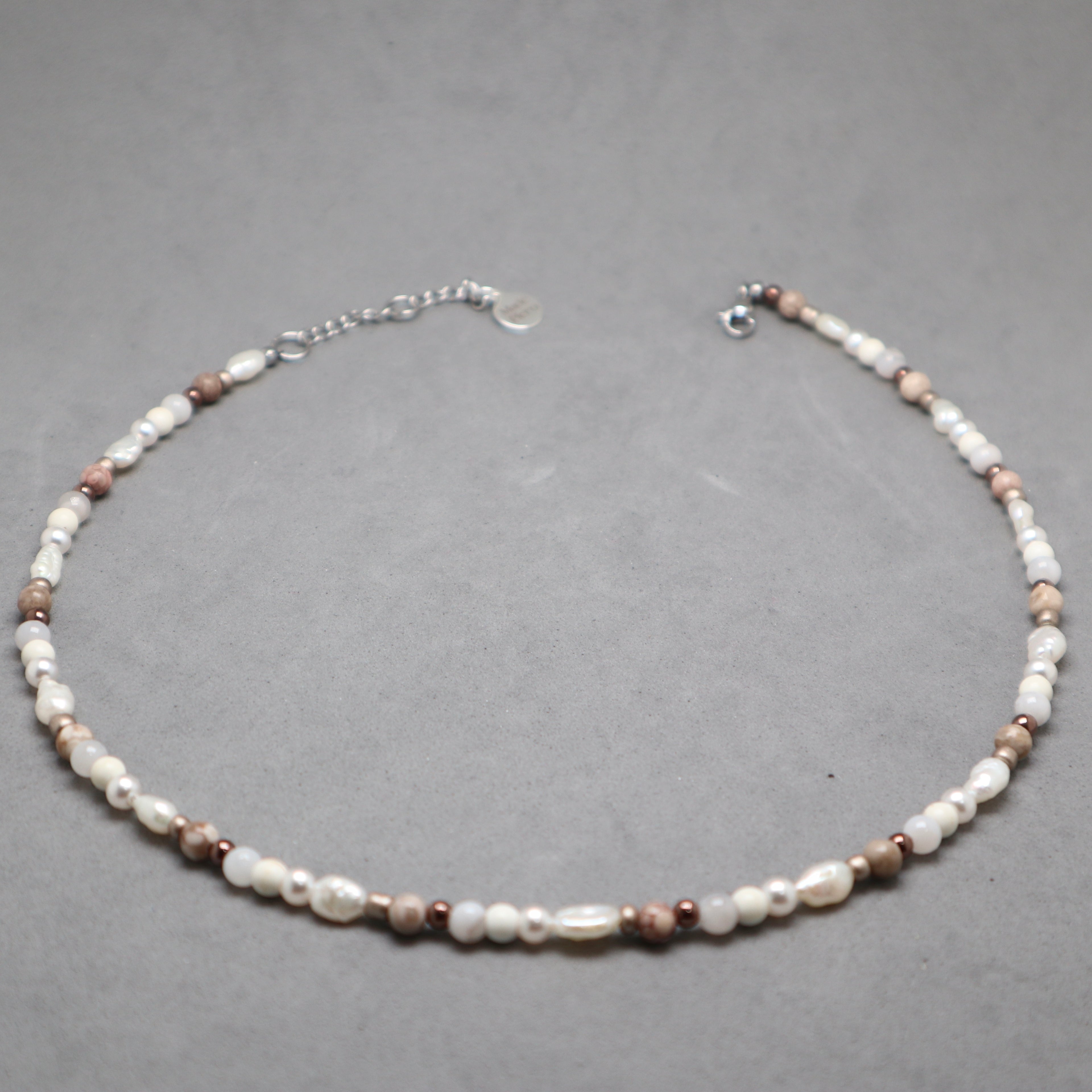 Necklace with pearls and brown beads on a gray background