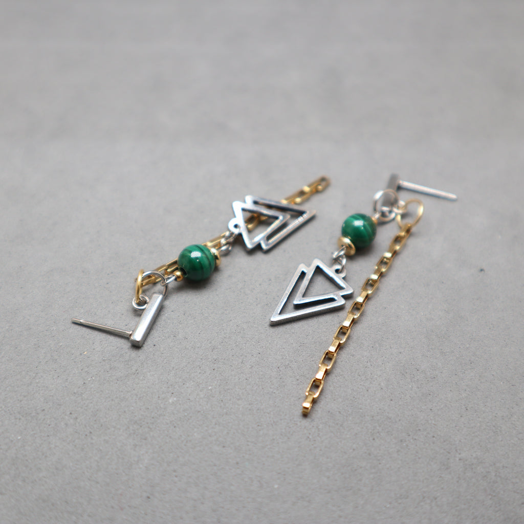 Pair of earrings with geometric designs and green beads on a gray background