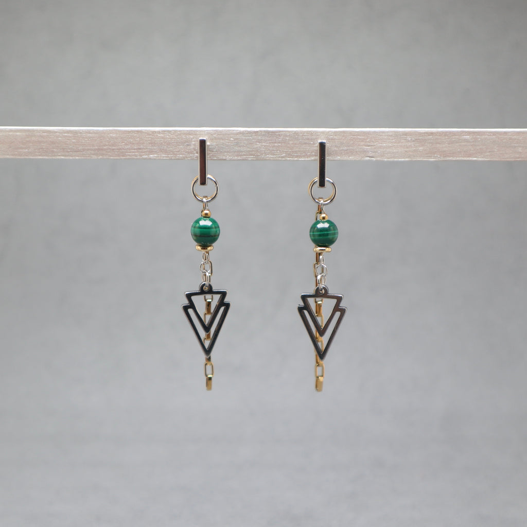 Pair of earrings with green beads and black geometric shapes on a gray background, malachite, stainless steel silver and gold