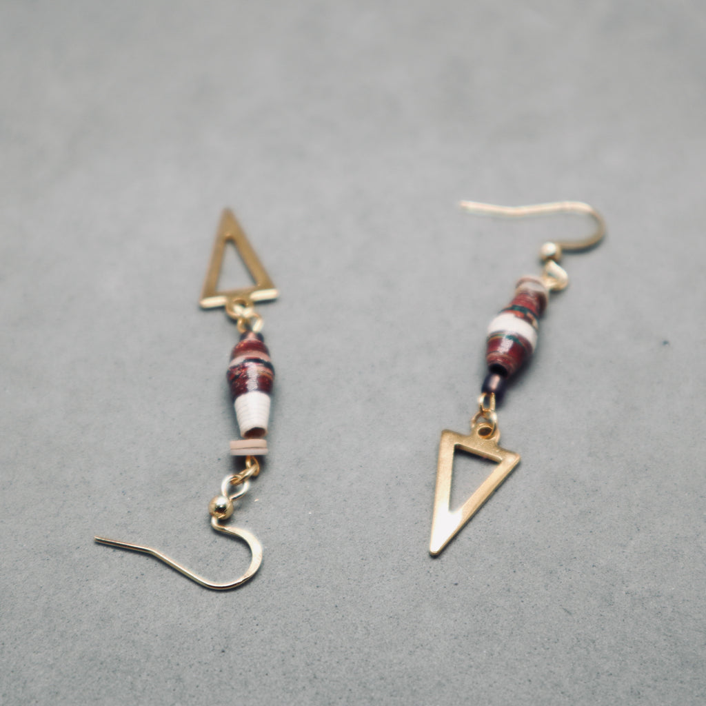 Pair of gold triangle and beaded earrings on a gray background