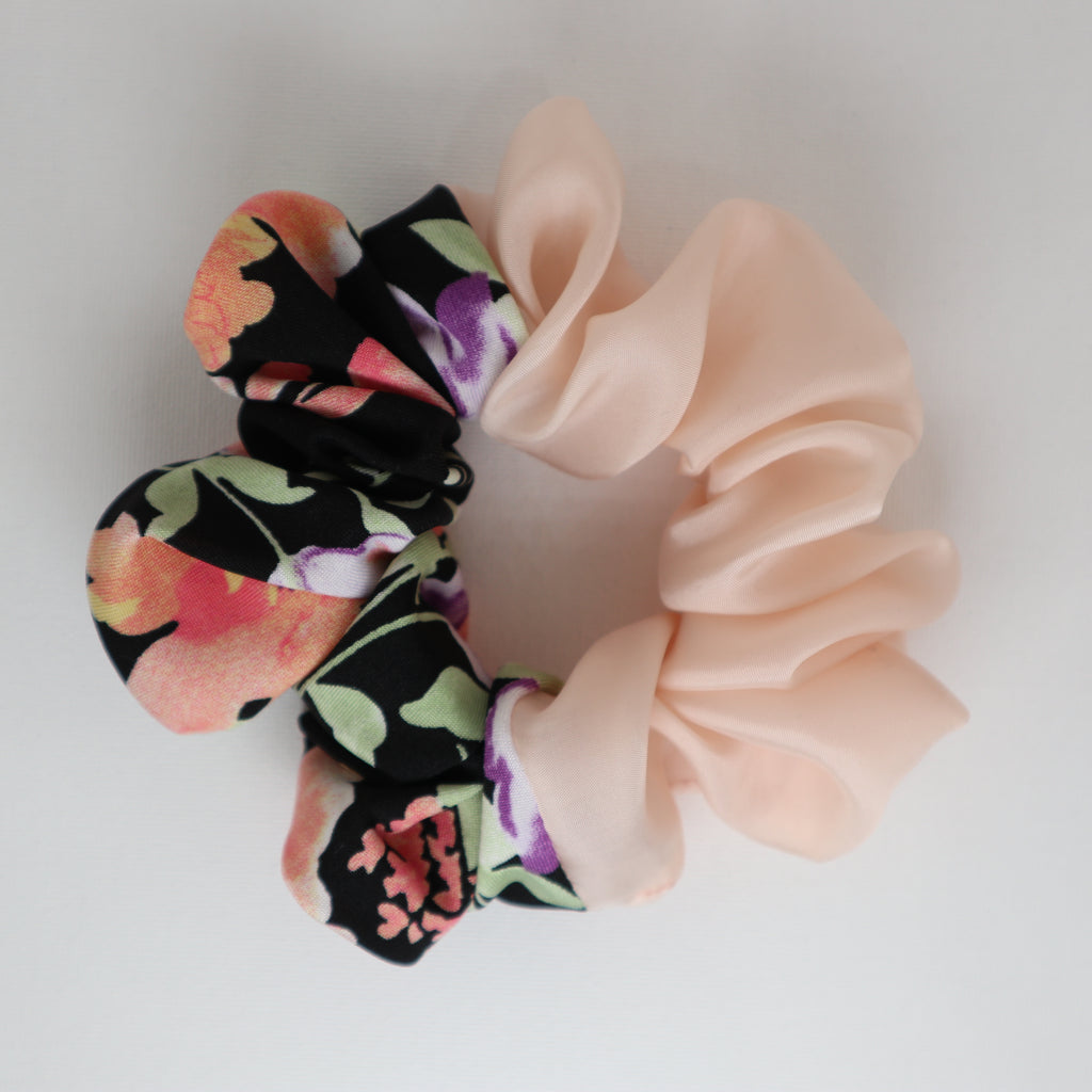Two colors scrunchies, one floral and one solid pink, on a light background