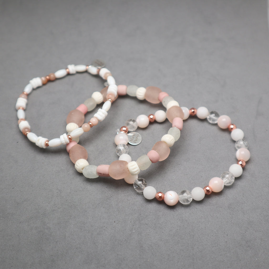 Set of three beaded bracelets on a gray background, bone, recycled glass, quartz, hematite