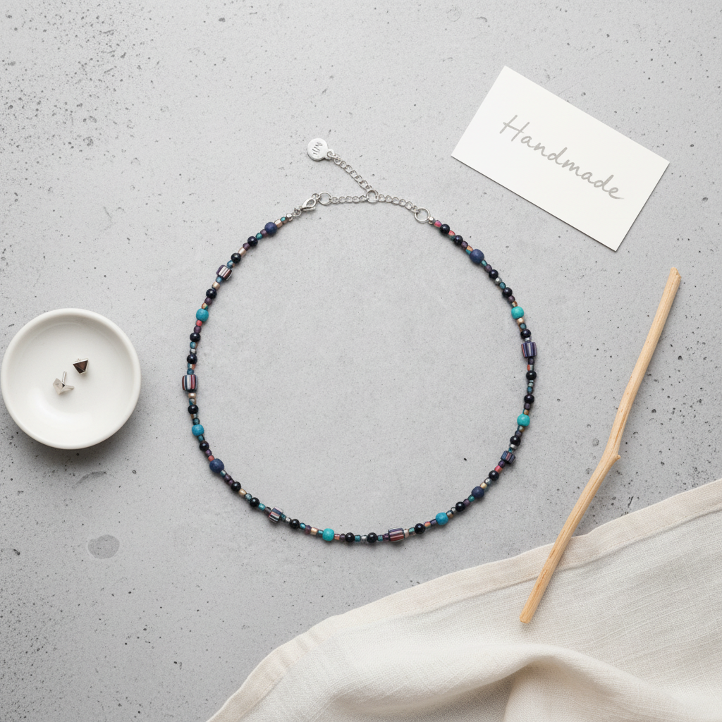 Handmade beaded necklace on a gray surface with a card labeled 'Handmade'., blue, turquoise, women
