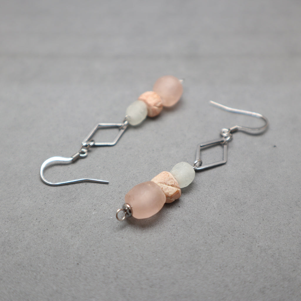 Pair of earrings with pink and green beads on a gray background