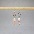 Pair of earrings with pink and white beads on a gray background, stainless steel, bone, recycled glass